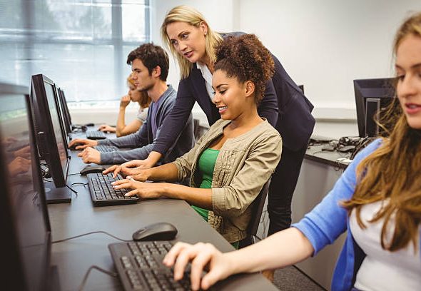 Attractive teacher helping her student in computer class at the university